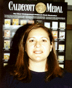 The photograph shows Grace standing in front of a Caldecott Medal  poster.