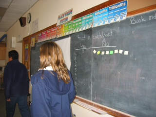 Students put their sticky notes on the board to show predictions.